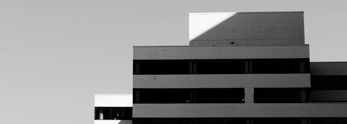 Minimalistische Gebäudefassade in Schwarz-Weiß mit klaren Kanten und dunklen Fensterbändern – Sinnbild für die strukturierte Objektbetreuung von Wehrheim Facility Management